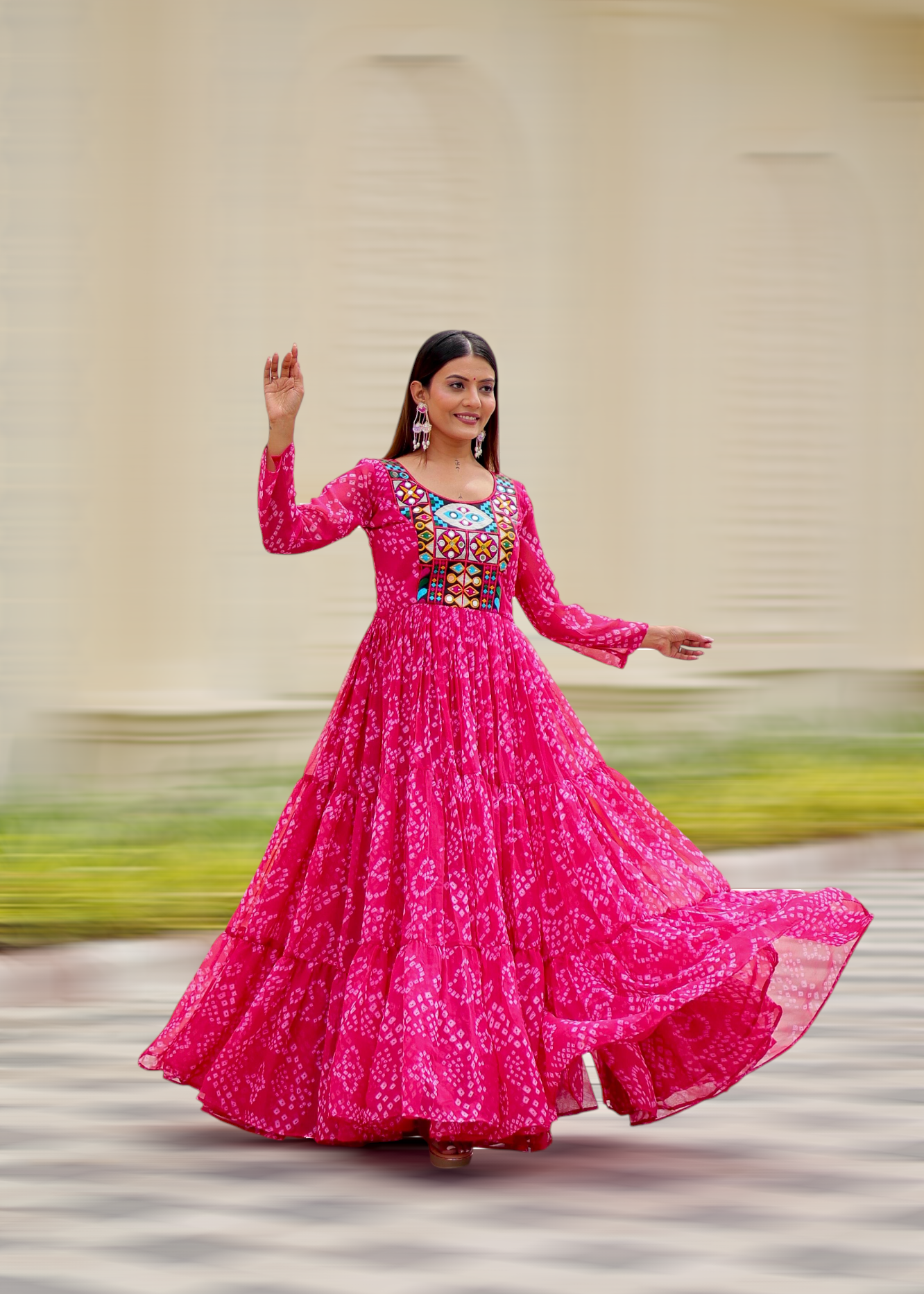 Woman in a bright pink traditional outfit with intricate patterns, standing outdoors.